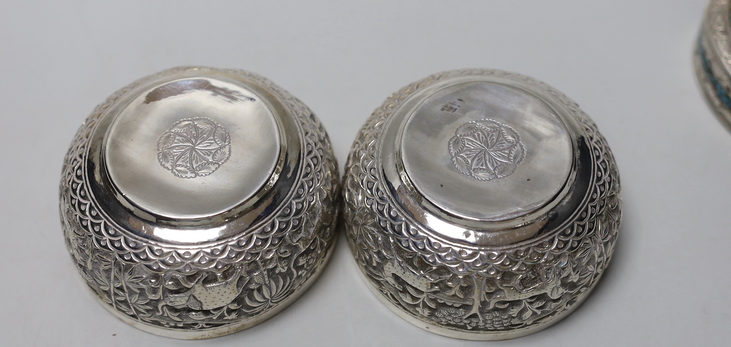 A pair of Indian embossed white metal finger bowls, diameter 97mm , a Persian white metal and turquoise set heart shaped paperweight and an Indian white metal and turquoise set heart shaped box.